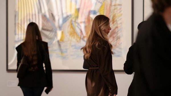 Visitors viewing contemporary artworks in a gallery setting, representing young artists, market visibility and the gap between attention and liquidity.