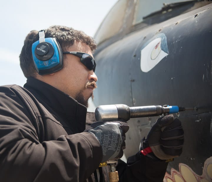 Student Federico Vigo, 31, removes screws from the plane to unlock a panel.