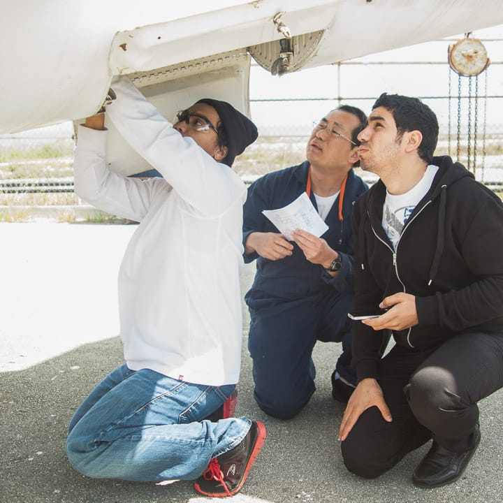 (L-R) Students Aries Gerald Pangan, 21, Peter Yuthrayard, 43, and Kerols Shafik, 25, inspect the Sabreliner T-39 air conditioning bay.