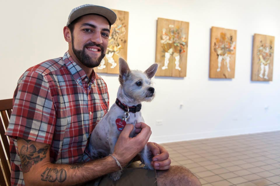 David Polka sits with his dog during the opening reception of his art exhibition at the City College Art Gallery, Thursday, Oct. 2. (Photo by Nathaniel Y. Downes)