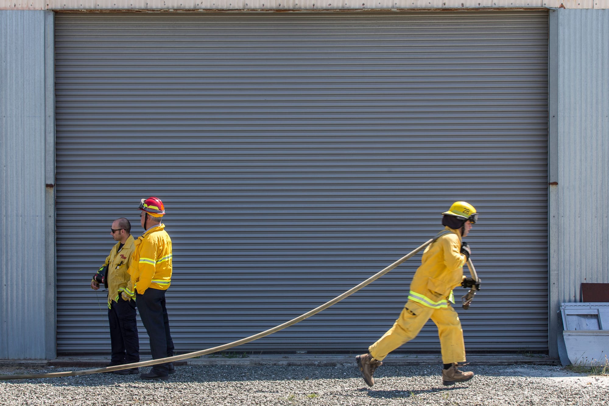 A fire cadet from City College’s Fire Fighter One Academy’s Class 15 runs a hose during a wlidland training drill while instructors look on at Cal Fire’s North Division Fire Station in San Mateo on Saturday, March 28, 2015. (Photo by Nathaniel Y. Downes/The Guardsman) 