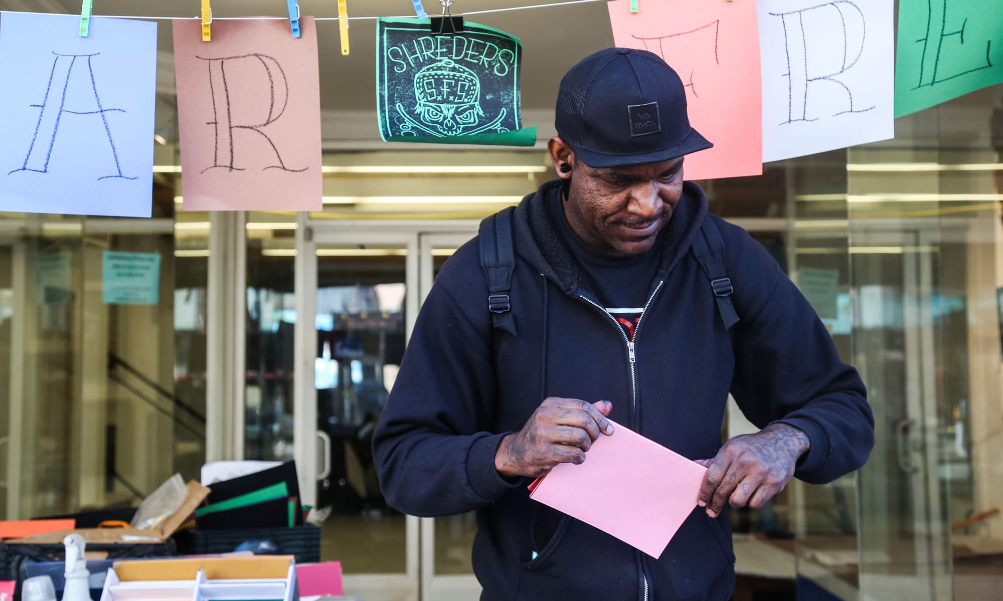 CAP staff member, Robert Chambers, making handmade greeting cards at the sidewalk art table at 1009 Market St.