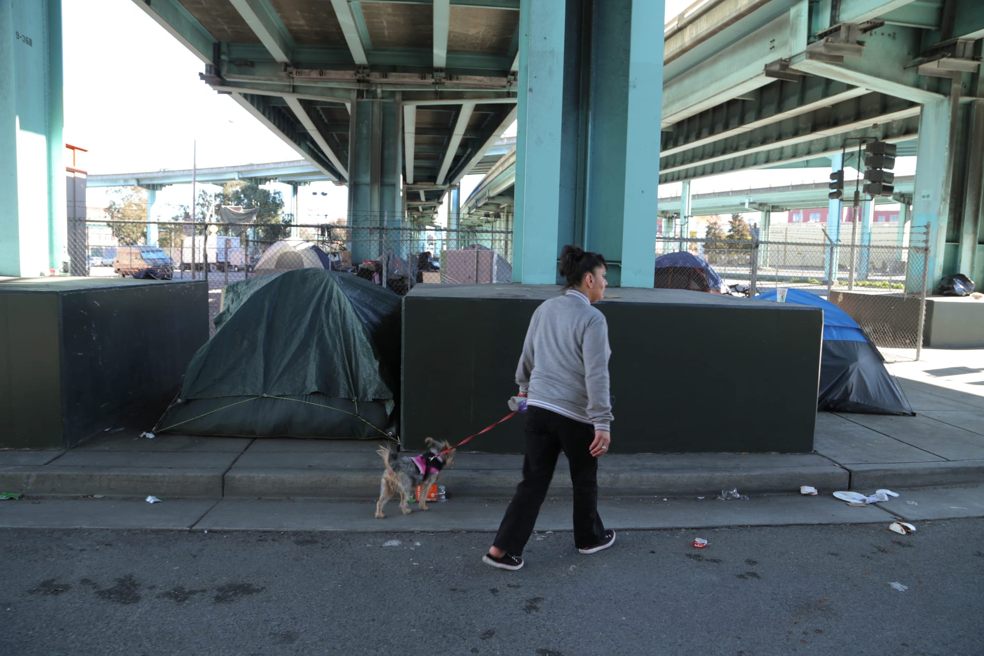 Jackie and her dog Tink look for her cousin underneath the US-101 overpass. They’ve lived in the camp for a couple months and consider themselves permanent residents. (Photo by Gabriella Angotti-Jones)