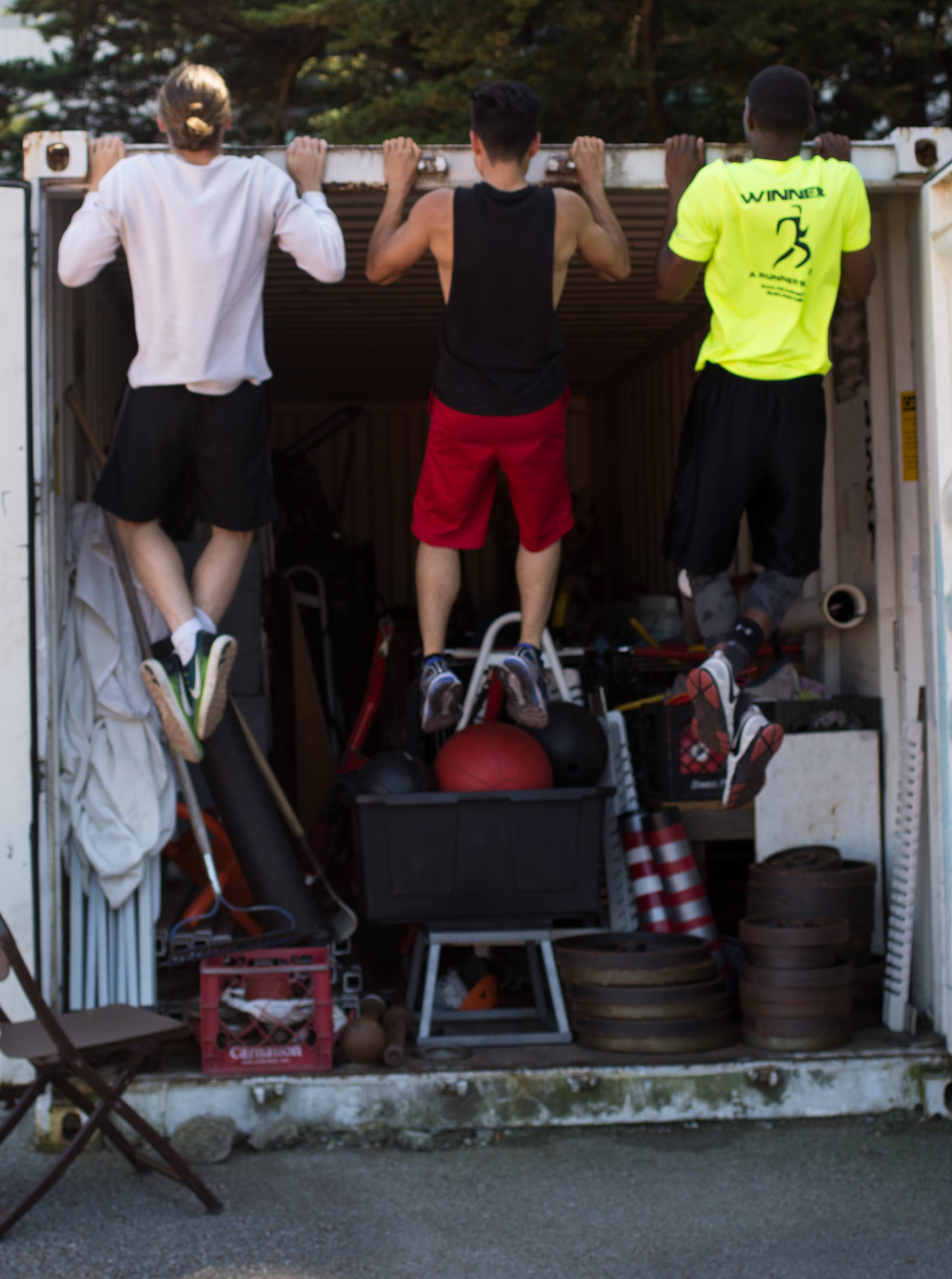 Rams track athletes Ronan Sullivan, Anthony Ismail and Rodney Morgan (left to right) do pull-ups using the edge of an equipment shed in the corner of the track field on May 1, 2017. (Nancy Chan / The Guardsman) 