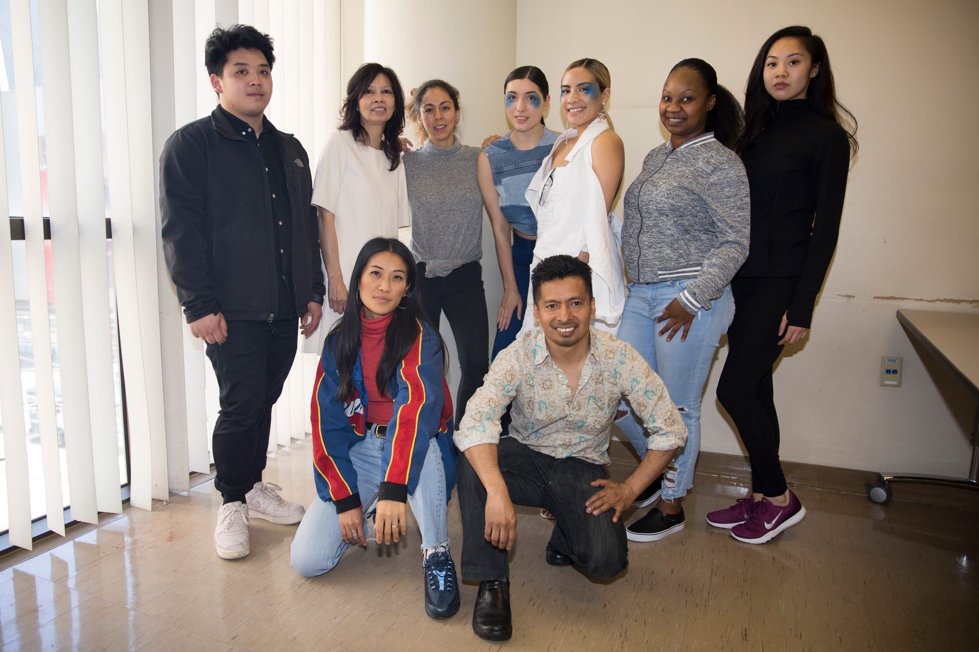 Designers, models, and others associated with the show pose in a group photo in Room 322 of Downtown Campus in San Francisco. From top left to right: Christopher Wong, Prof. Priscilla Fong, Sara Espinoza, Inna Nikolskaia, Daphne Dominia, Emerald Gilbert, Renee Gee. From bottom left to right: Natasho Lo, Enrique Chavez. Photo by Alexander Wong/Courtesy of Alexander Wong. 