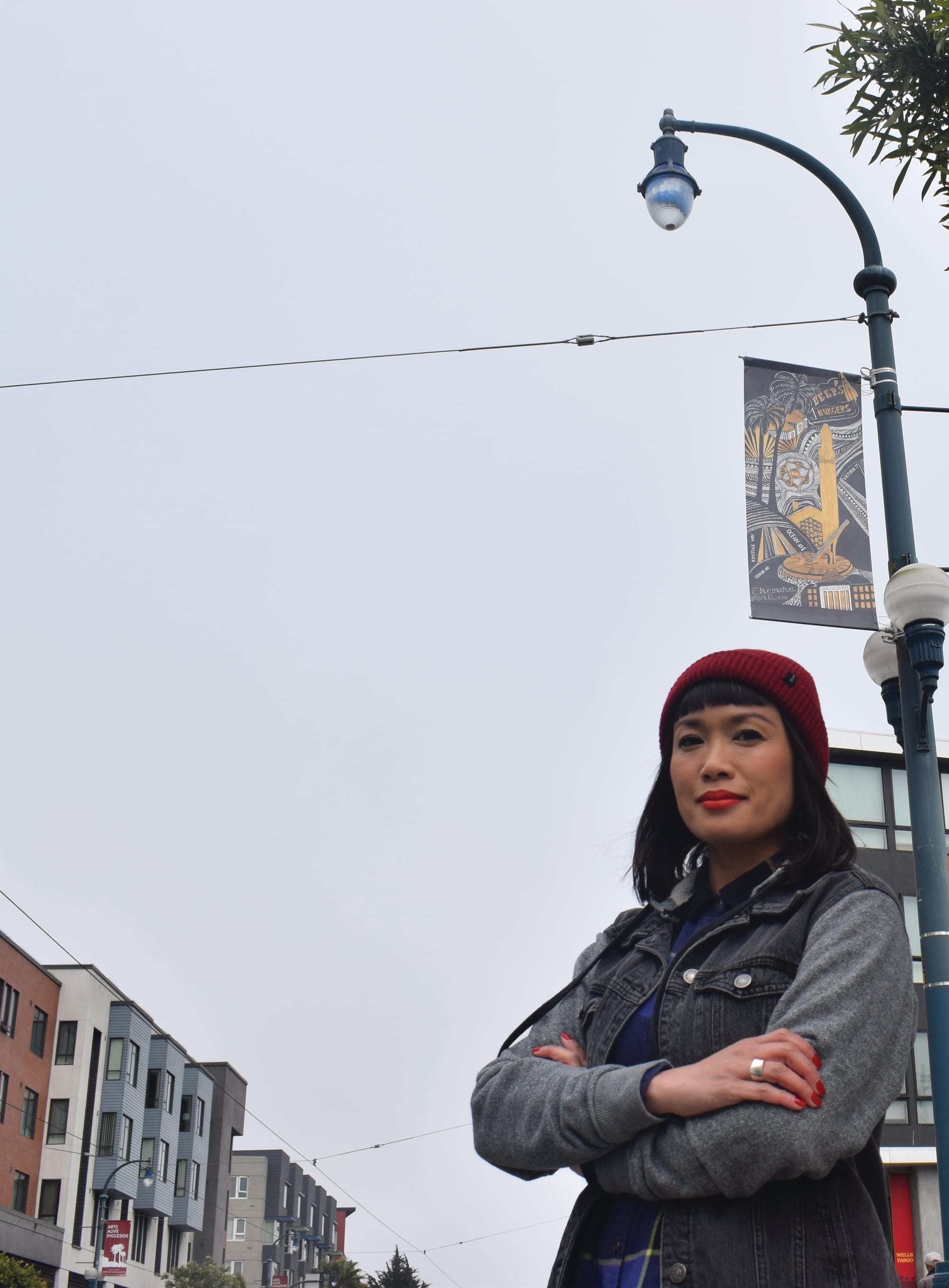 Award winningartist and photojournalist, Ekevara Kitpowsong stands in front of her artwork displayed on vinyl banners alongside Ocaen Avenue. Photo by Sarah Berjan