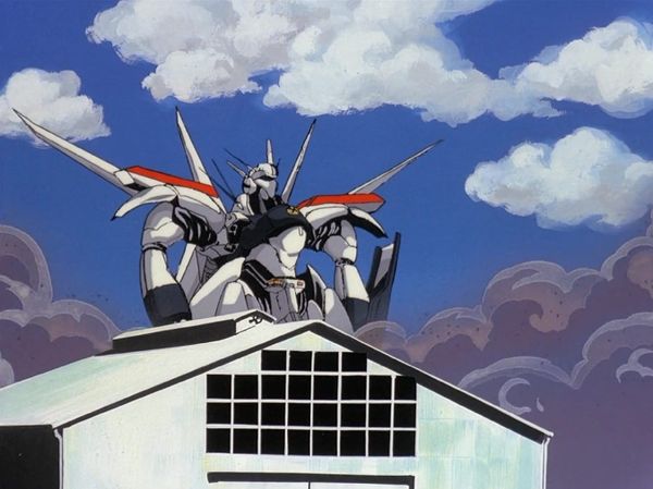 An image from Patlabor episode Longshot where an oversized Patlabor robot with awkward wings looms over a warehouse, with black smoke behind it, and a blue sky full of fluffy white clouds.