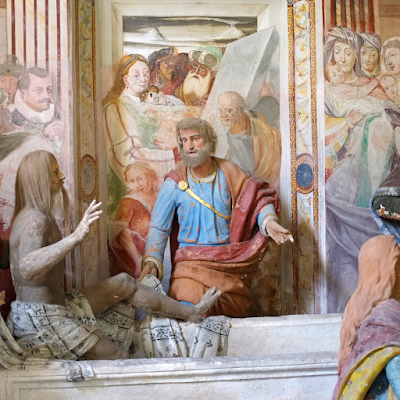 Museum exhibit showing wax figures against Renaissance-like painted walls
