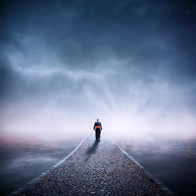 Priest walking a lonely stone road into the horizon