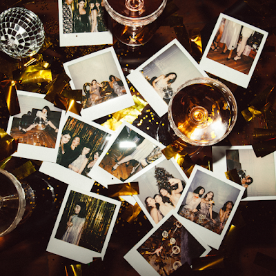 Polaroid photographs and a drink on a wooden table.