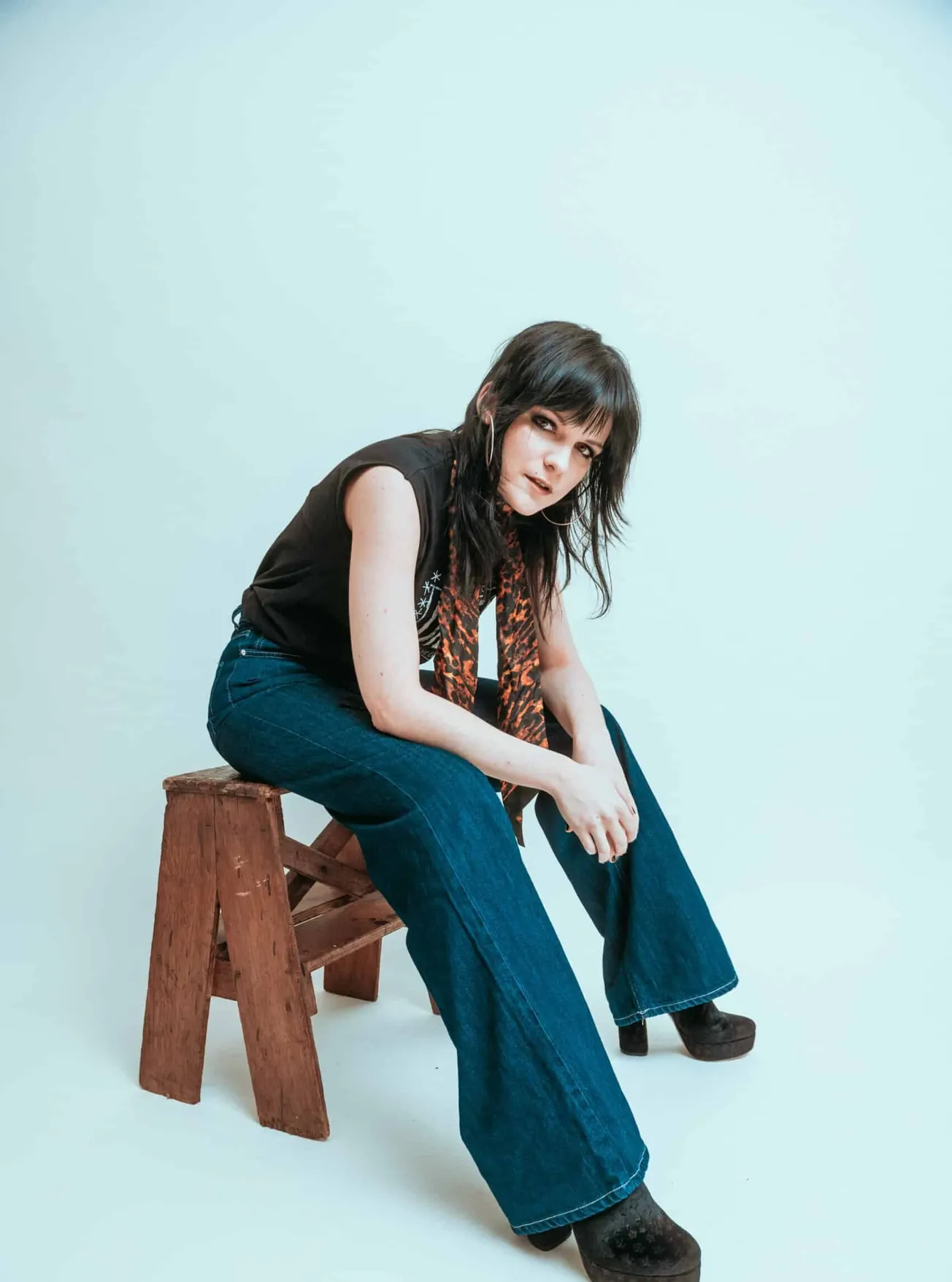 Actor, writer, producer and access coordinator Abbie Hills sitting on a stool and looking at the camera. She wears a black to