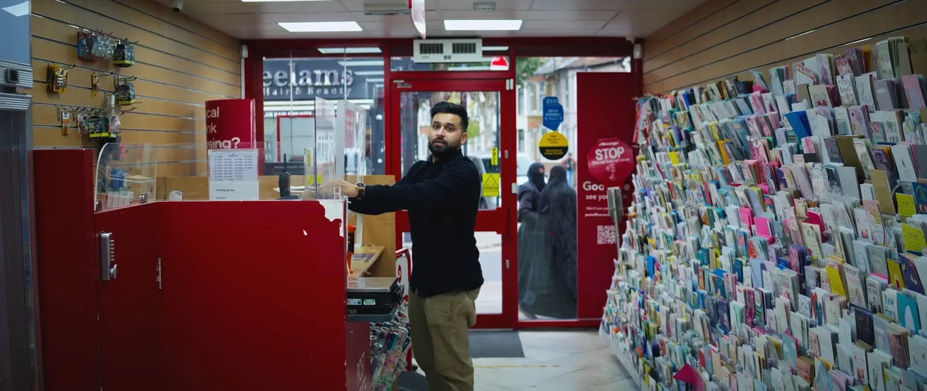 A still from 'Go Back to Your Country' showing Islah Abdur-Rahman's character Omar standing in his family's shop.