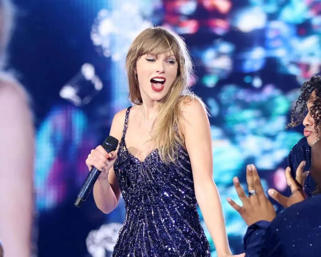 Taylor Swift performs on stage in Detroit wearing a sparkling black leotard.