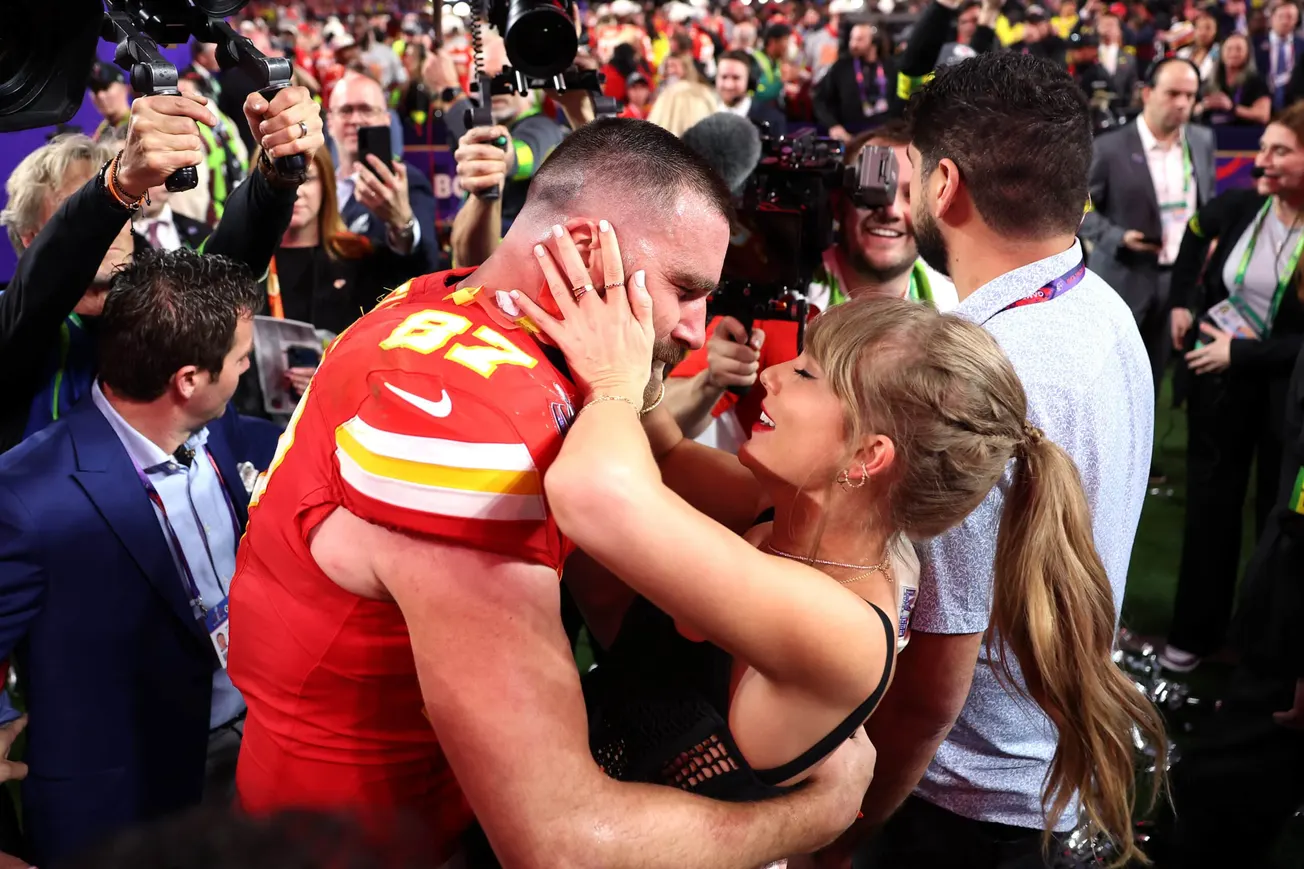 Travis and Taylor embracing with photographers behind them.