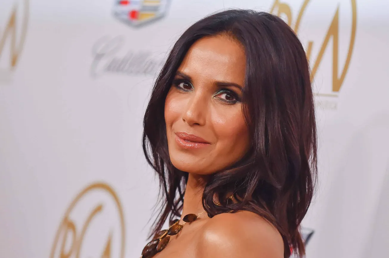 Padma Lakshmi smiles at a press event, wearing a strapless dress.