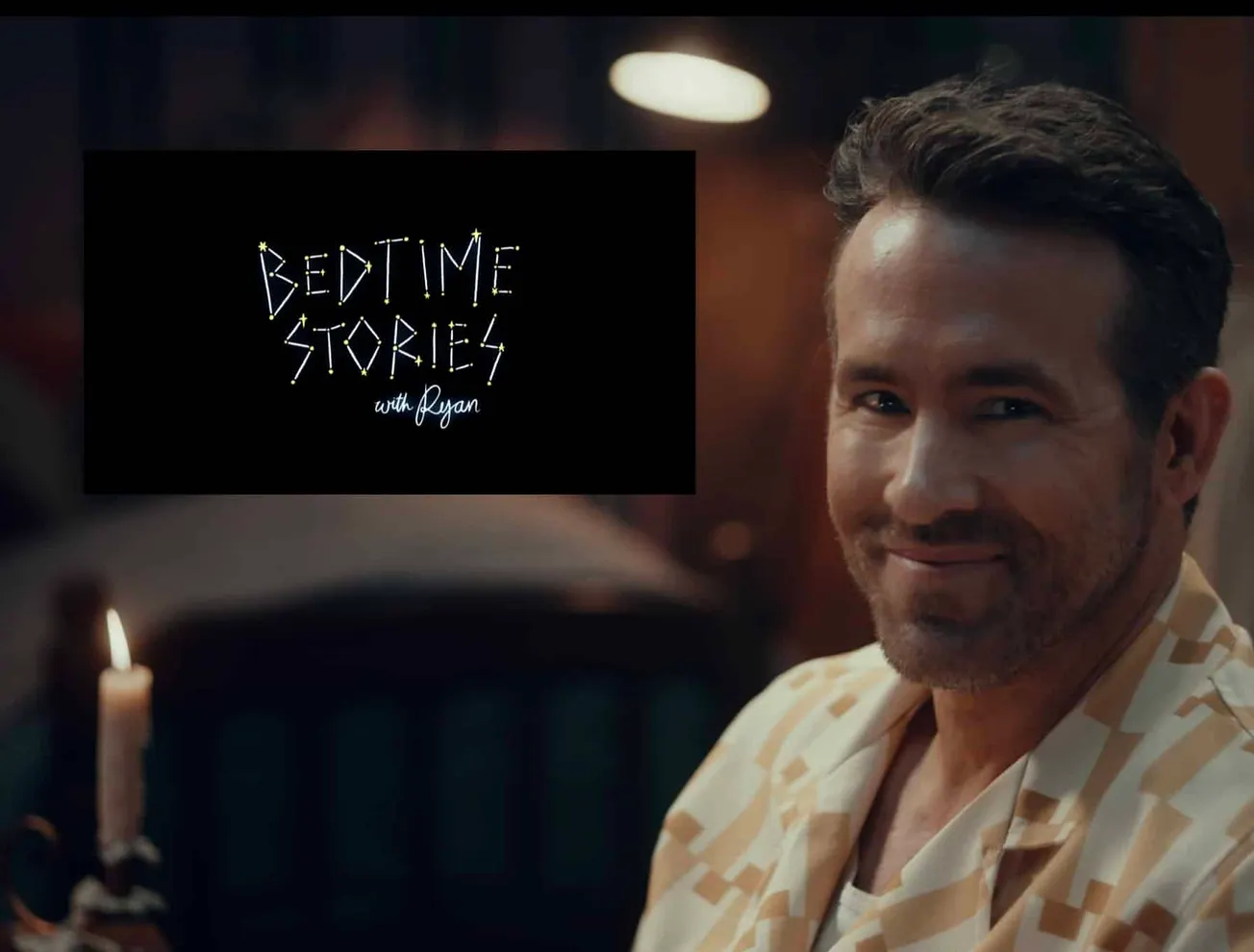 Bedtime Stories with Ryan Reynolds. A photo of Ryan smiling in his pyjamas with a candle lit beside him.