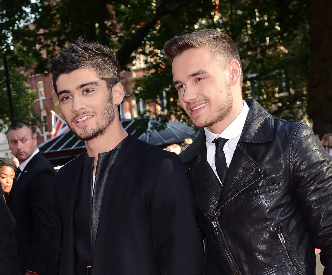 Zayn Malik and Liam Payne at a red carpet event. They're smiling together and both dressed in black