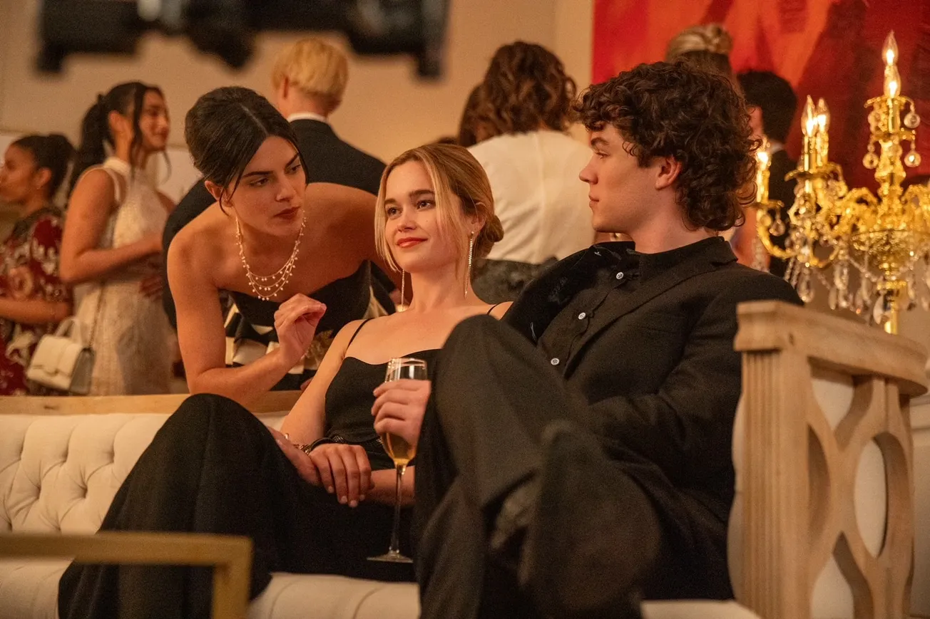 A still from the 2024 Cruel Intentions series on Prime Video showing three people on a couch dressed in formal wear, talking