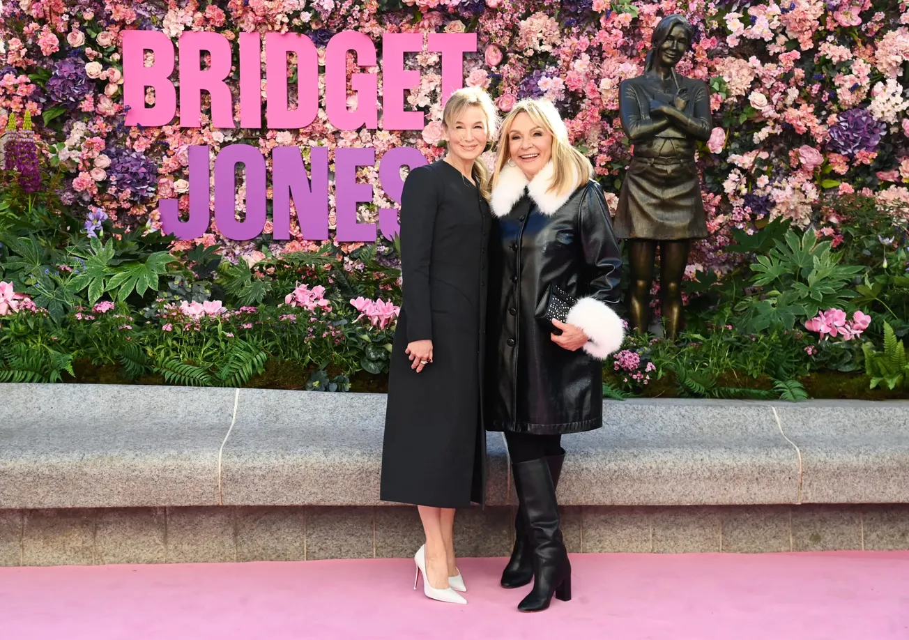 Renee Zellweger and Helen Fielding smimle together in front of a Bridget Jones bronze statue