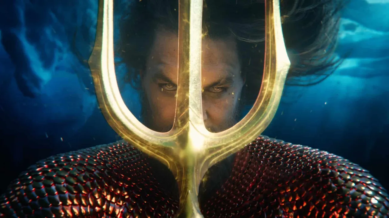 A still from Aquaman & The Lost Kingdom showing Jason Momoa's character under the ocean, staring through a gold trident.