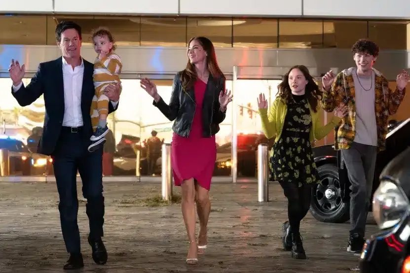 Mark Wahlberg holding a baby and his family all with their hands up in a still from 'The Family Plan' trailer