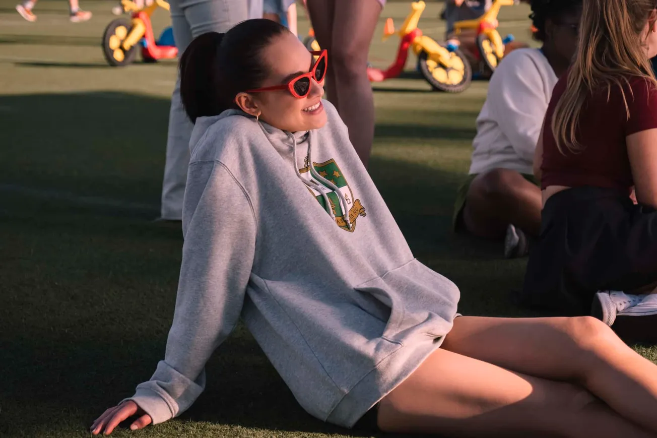 A still of Belly smiling in red sunglasses and a grey hoodie from The Summer I Turned Pretty Season 3