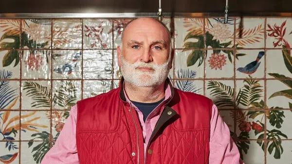 Chef José Andrés smiles wearing a red shirt and vest. He has a white beard