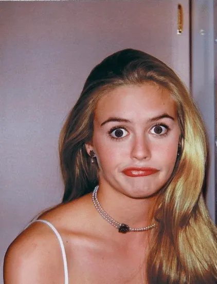 Headshot of Alicia Silverstone on the set of Clueless. She has long blonde hair and is making a funny face.