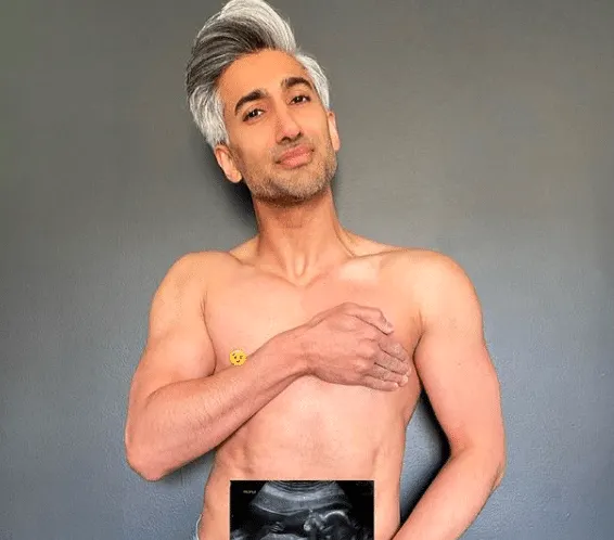 Tan France is topless and holds an ultrasound photo of her his stomach.