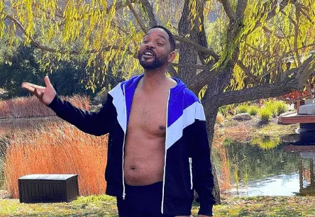 Will Smith posing in a garden with his jacket unzipped. He's wearing undies and has a visible belly.