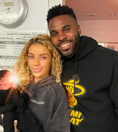 Jena Frumes and Jason Derulo take a family photo with their new baby boy in hospital. His face is covered with a shining filt