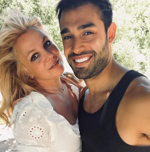 Britney Spears and Sam Asghari smile in a photo taken in a garden.