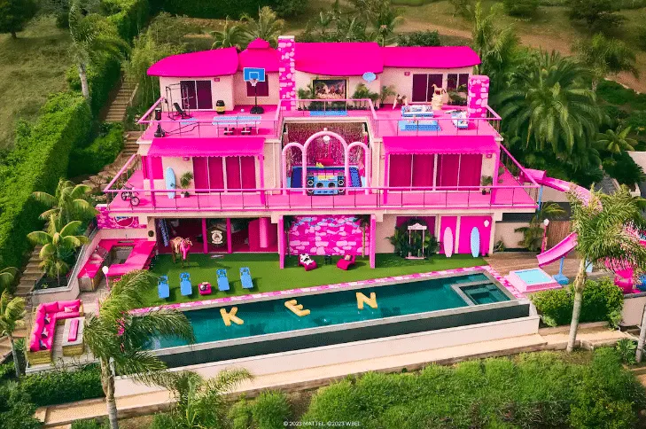 Barbie's Malibu Dream house is available to rent on Airbnb. This photo shows a three storey pink mansion with a pink slide an