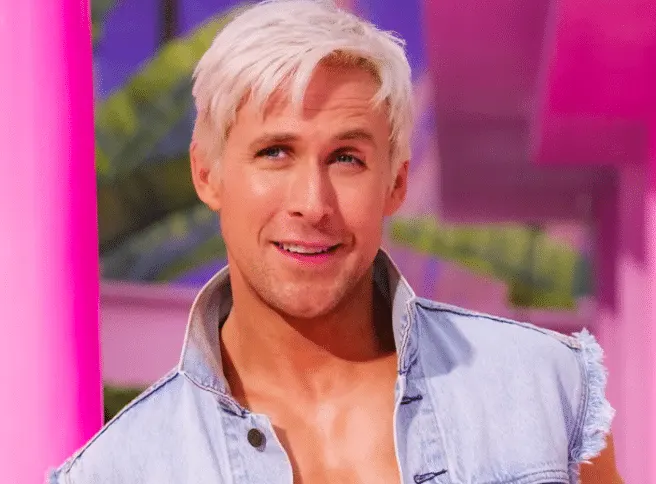 Ryan Gosling as Ken in the Barbie film 2023. He has bleached blonde hair and wears a ripped denim vest.