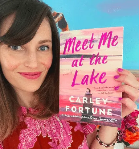 Author Carley Fortune holding a copy of her book "Meet Me at the Lake" which is being adapted for Netflix by Meghan and Harry