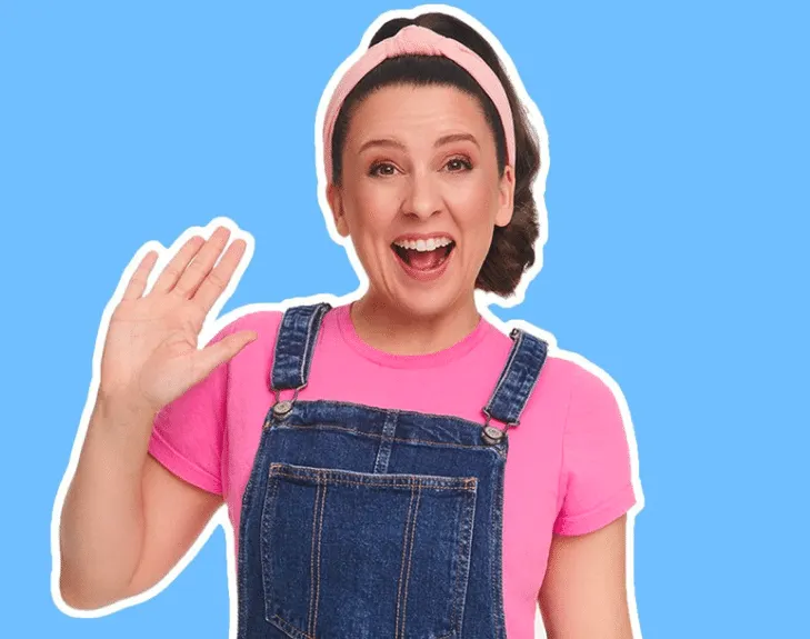 a still of Ms Rachel smiling, she wears a pink t-shirt and overalls with a matching pink headband. The photo is used for her