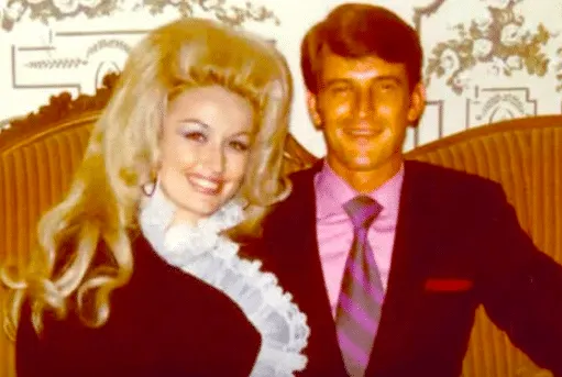 Dolly Parton and Carl Dean smiling together on a couch