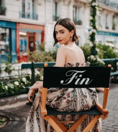 Lily Colllins from 'Emily in Paris' sitting in a chair with the word "Fin" on it