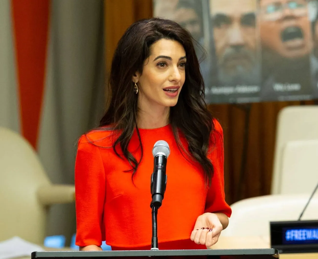 Amal Clooney speaks at the United Nations in 2018 wearing a red suit.