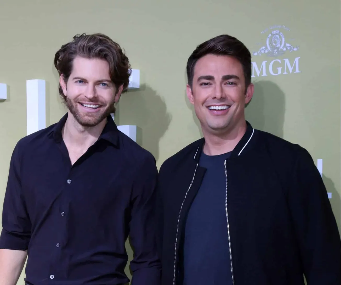 Jaymes Vaughan and Jonathan Bennett at a red carpet event. Jaymes wears a blue shirt and has some facial stubble. Jonathan we