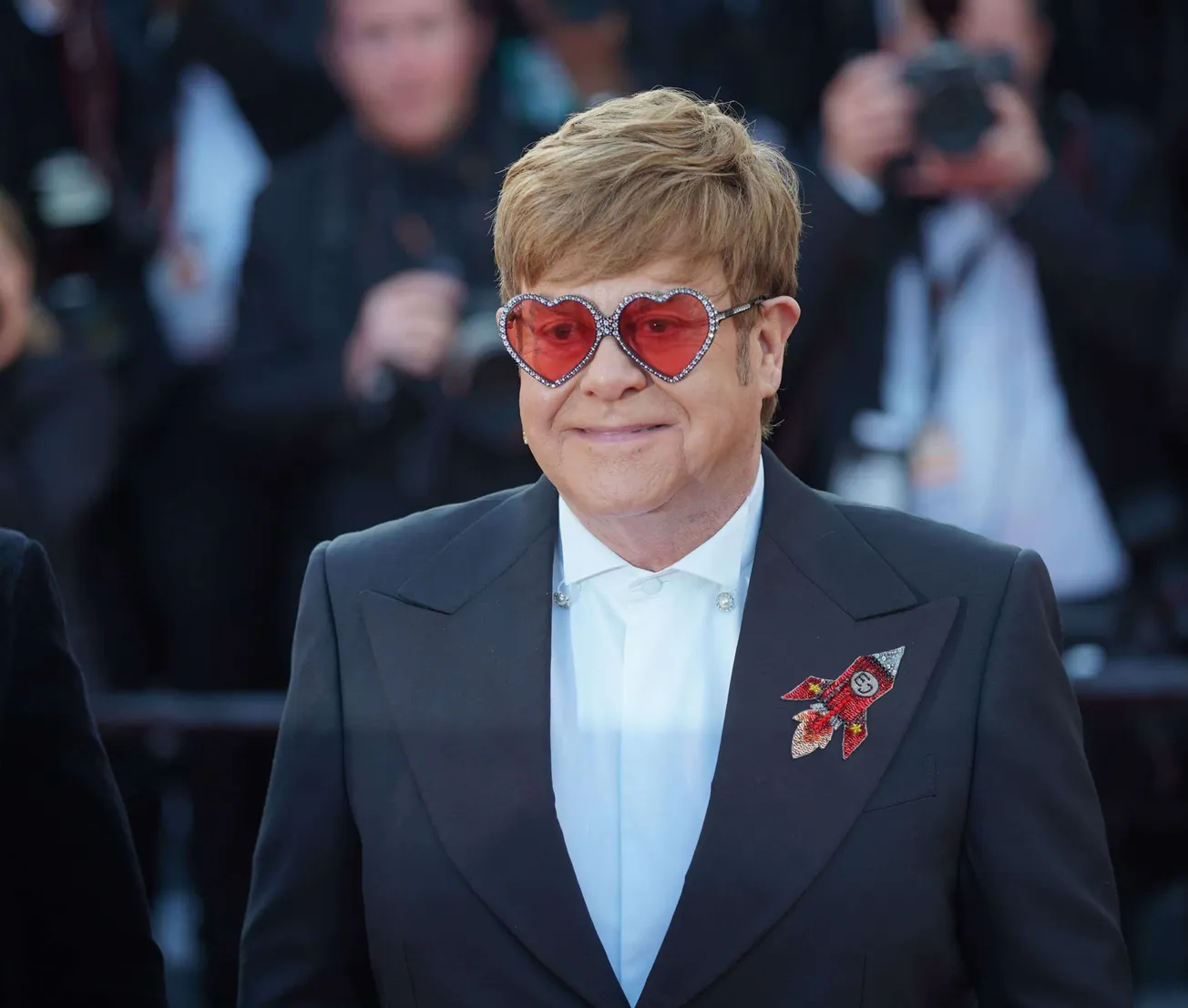 Sir Elton John wears heart shaped sunglassed and a blazer with a rocket stitched onto it. He recently performed his final far