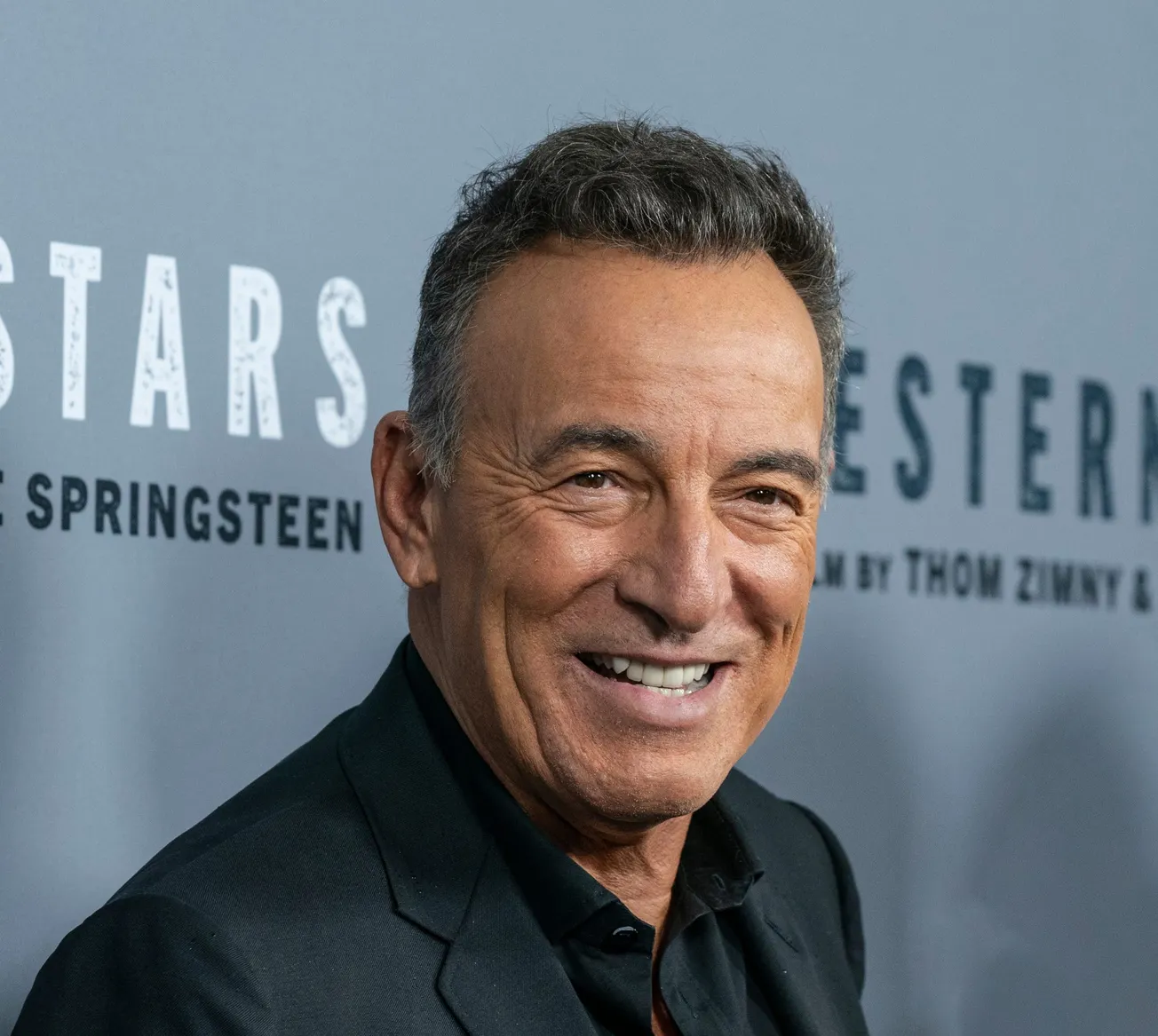 a close up photo of Bruce Springsteen smiling at a press event