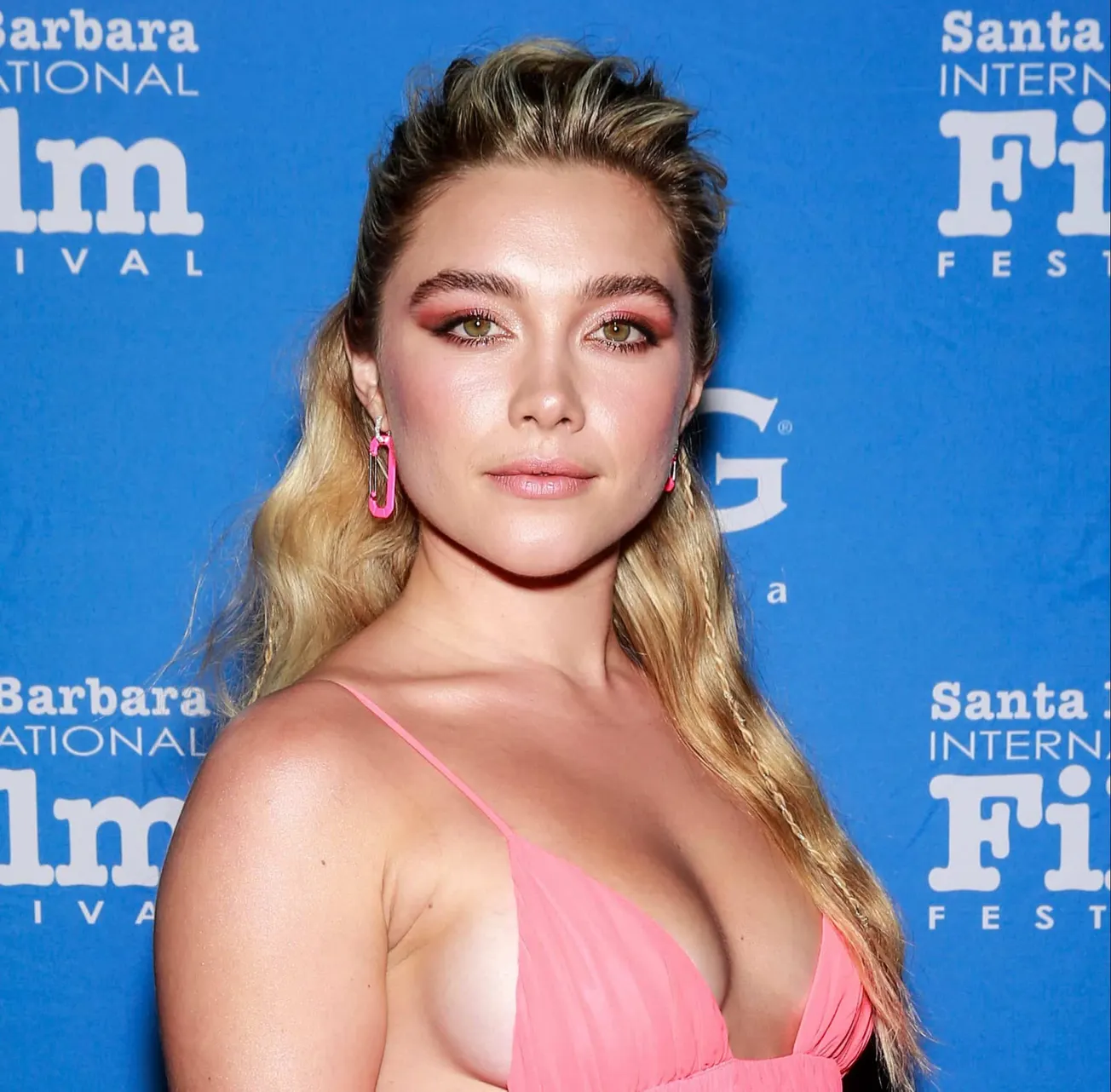 Florence Pugh attends a red carpet event. She has long blonde hair, half is tied back away from her face. She wears a pastel