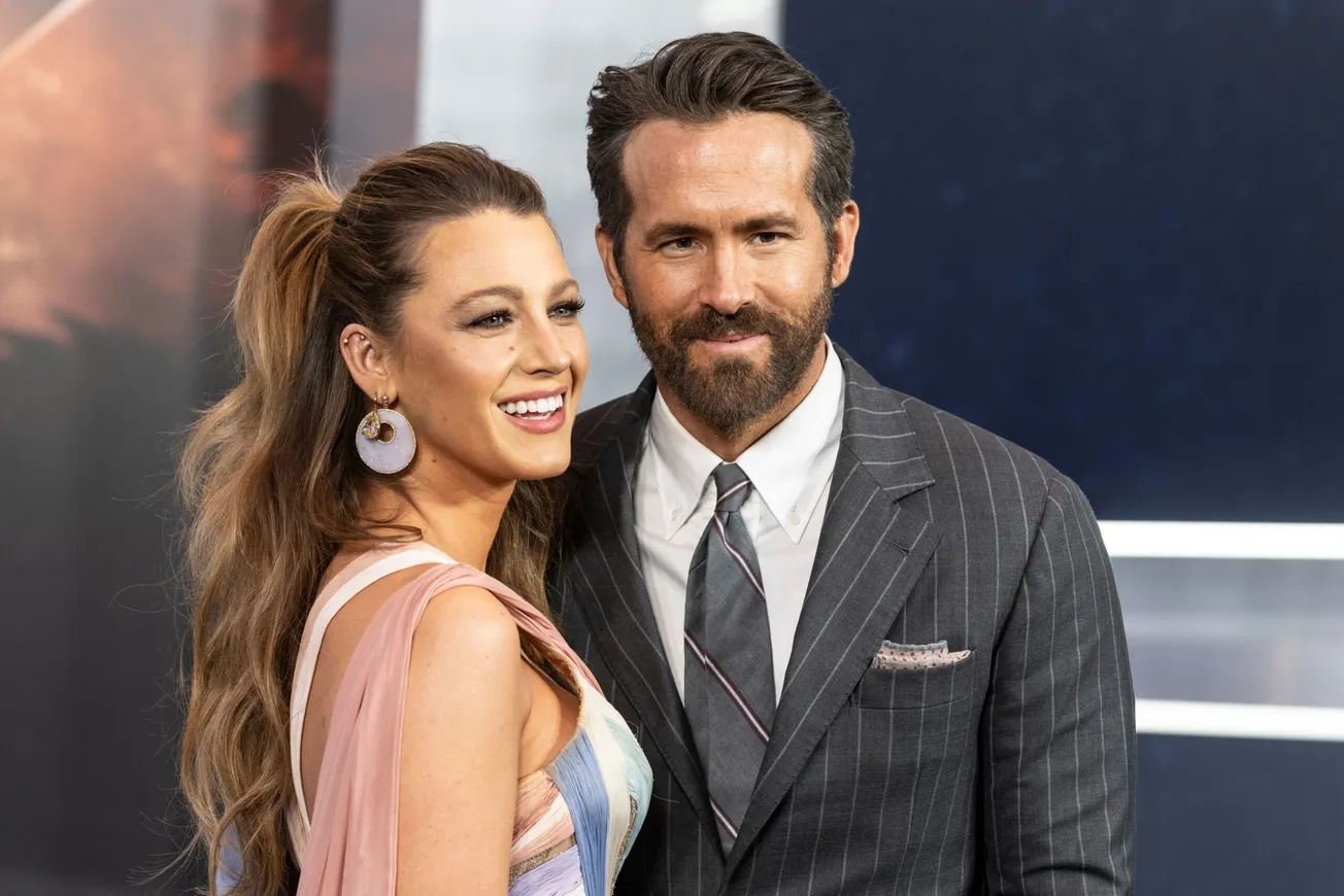 Blake Lively and Ryan Reynolds smile together for a photo ar a red carpet event in 2022.