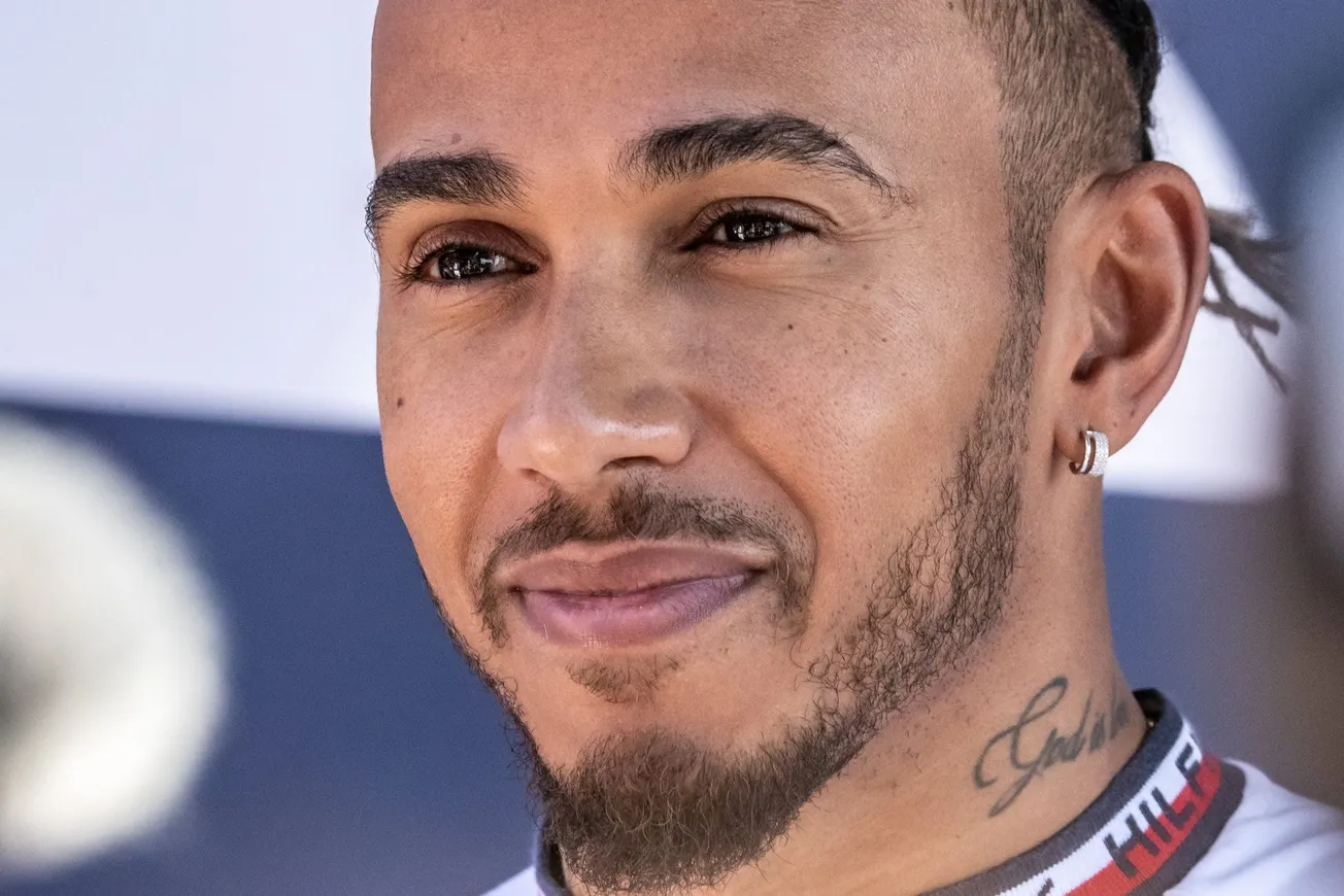 a close up of Lewis Hamilton smiling at a racing event.