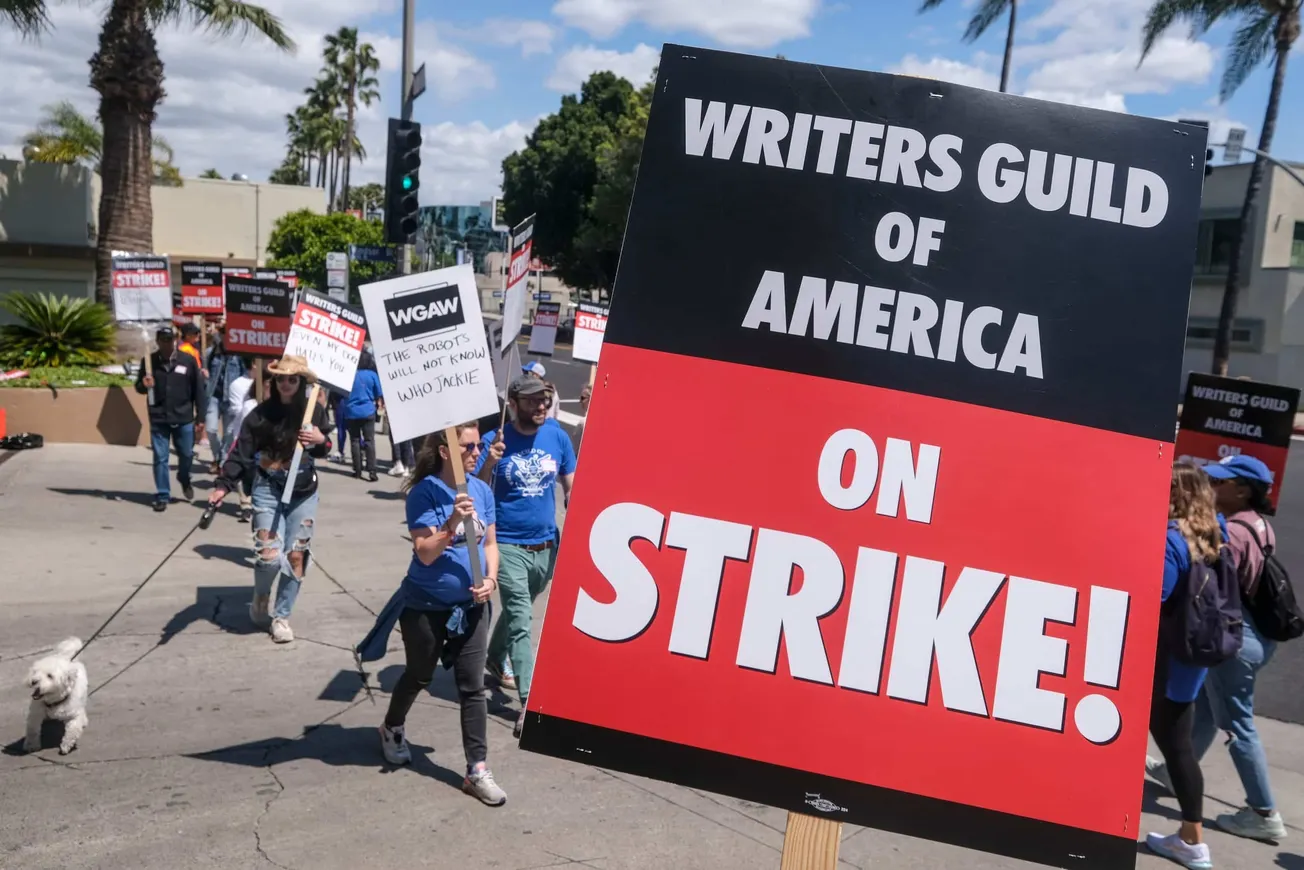 striking writers from the writers guild of america holding signs showing they are on strike