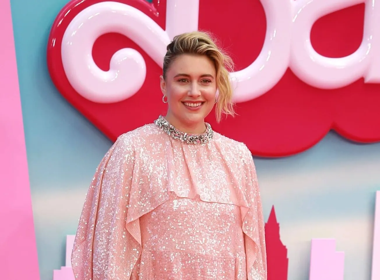 Greta Gerwig smiles at a Barbie press event dressed in pink. Ryan Gosling recently celebrated her 40th birthday by sending he