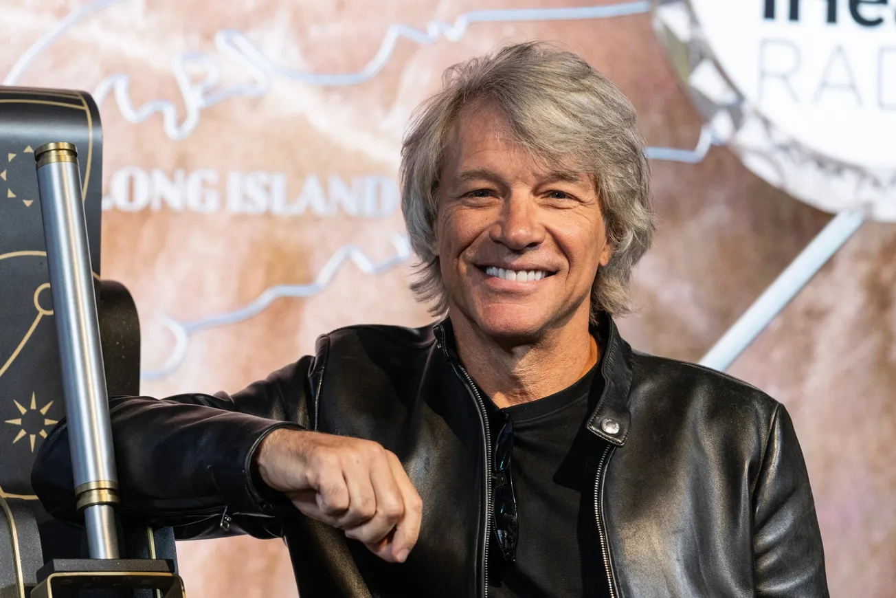Jon Bon Jovi smiles at a press event wearing a leather jacket