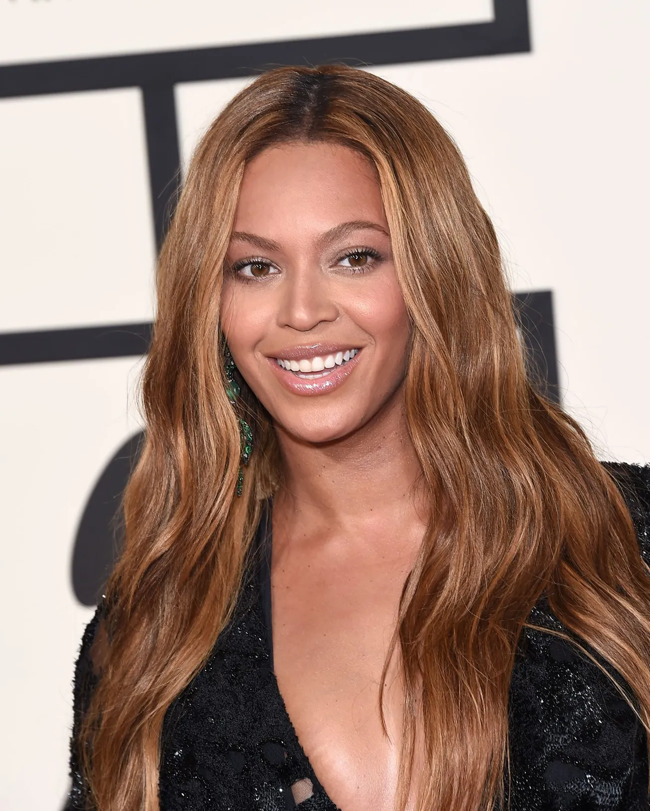 Beyoncé smiles at a press event with her long brown hair sitting in waves over her shoulders. Today she has hinted she's work