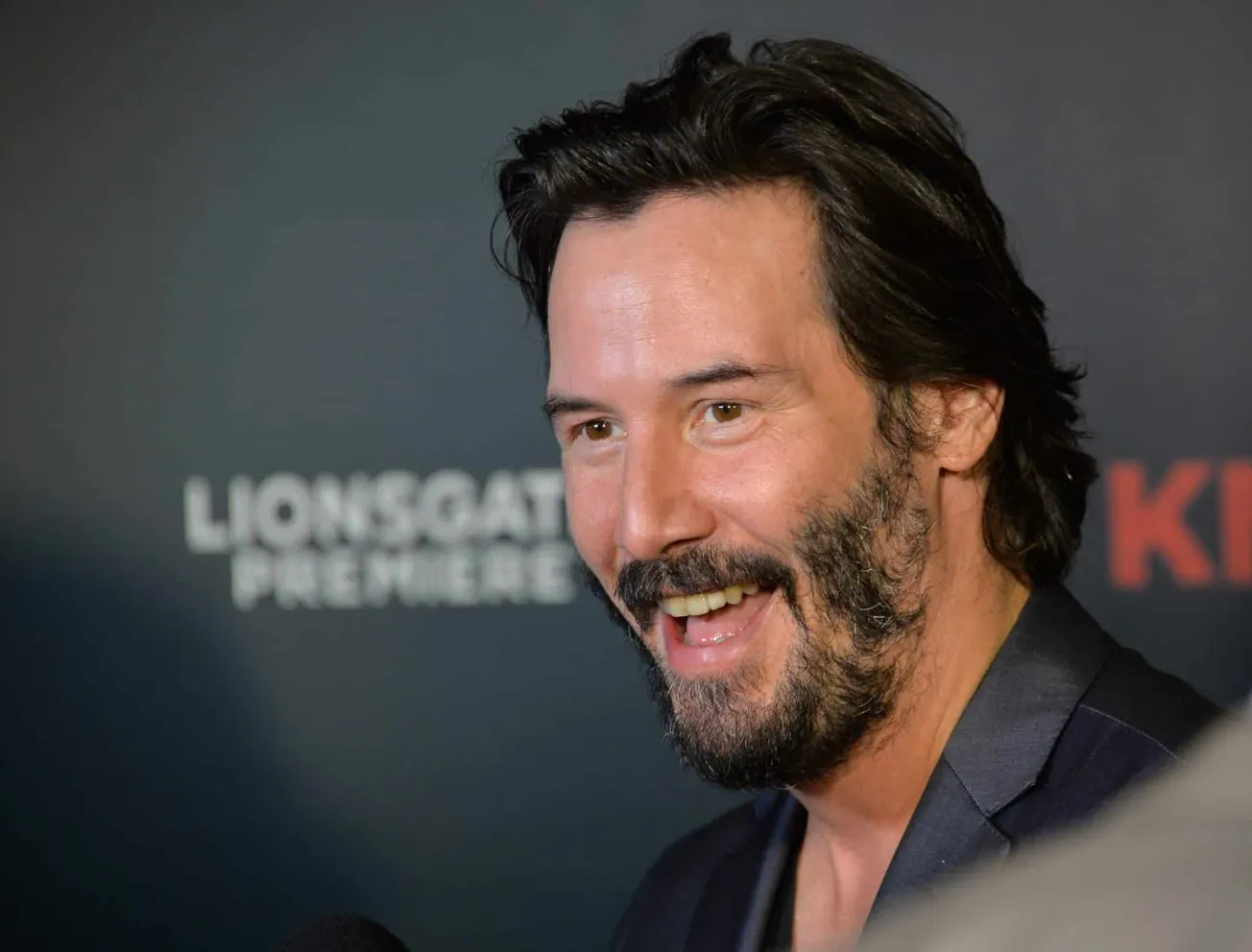 Keanu Reeves laughing at a press event.